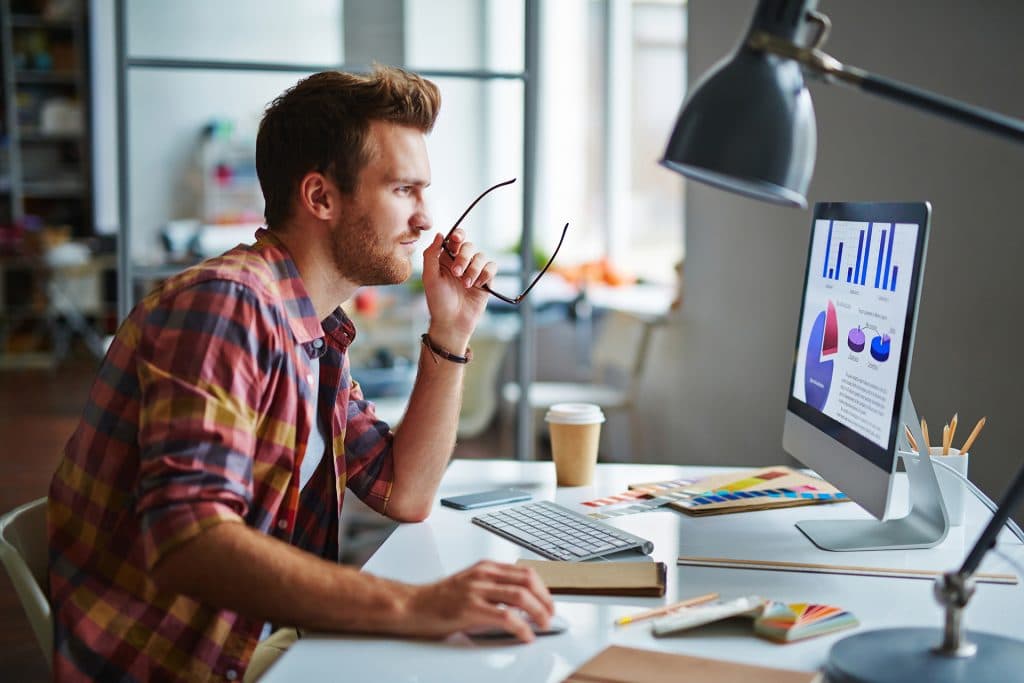 Man holding glasses working on computer