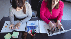 two woman working together at a desk