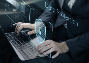 Image of person typing on a laptop keyboard with a holographic shield and the words 'Data Protection' projected above